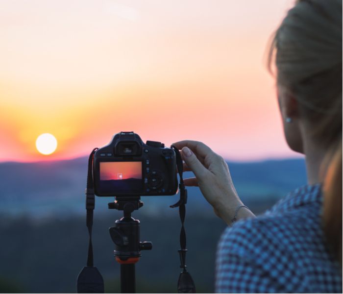 Woman photographing sunset